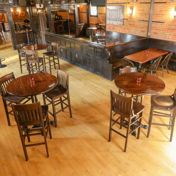 Interior of Firebird Tavern, showing high-top tables, chairs, and booths with brick walls and wood paneling.