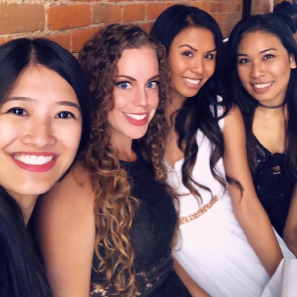 Four smiling women posing together in front of a brick wall at Firebird Tavern.