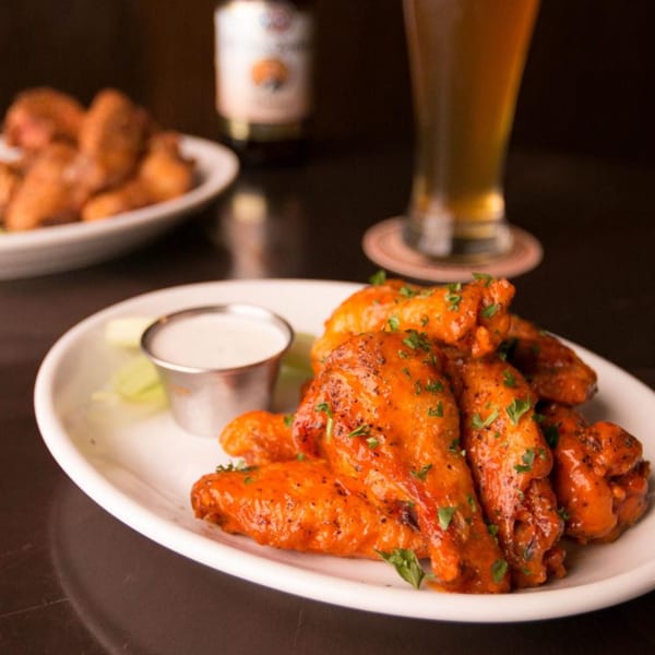 Firebird Tavern's buffalo wings with ranch dressing and celery, with a beer in the background.