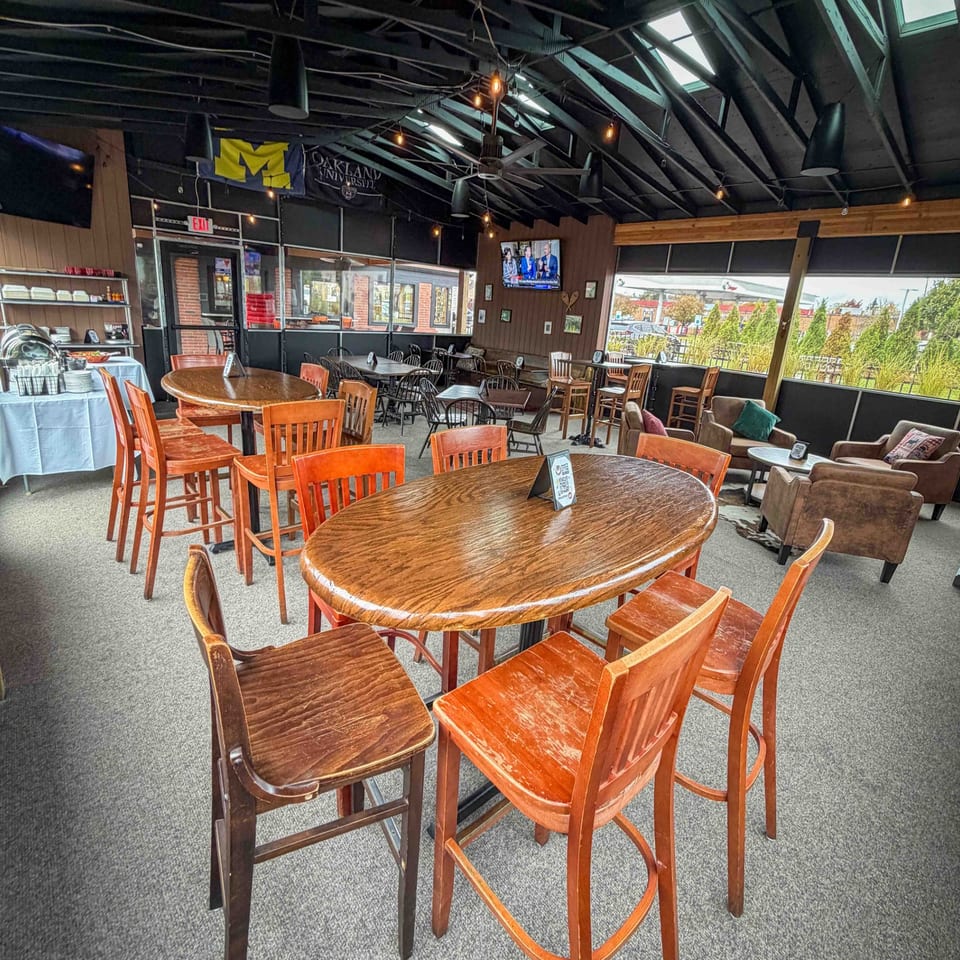 Spacious Firebird Tavern dining area with high-top tables, bar stools, and lounge seating under a vaulted ceiling.