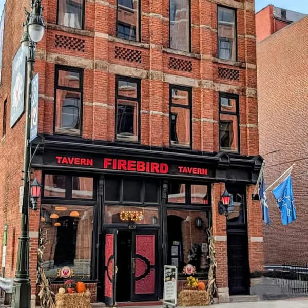 The Firebird Tavern, a brick building with black trim and red doors, decorated for autumn.