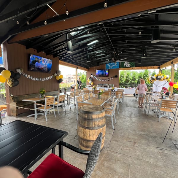 Spacious outdoor patio at Firebird Tavern with tables, chairs, graduation decorations, and TVs.