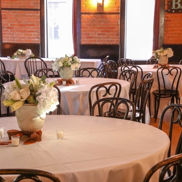 Elegant dining room at Firebird Tavern with round tables, white tablecloths, and floral centerpieces.