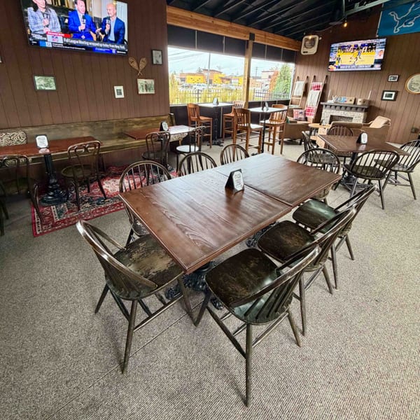 Interior of Firebird Tavern, showing dining tables, chairs, a fireplace, and TVs with sports.