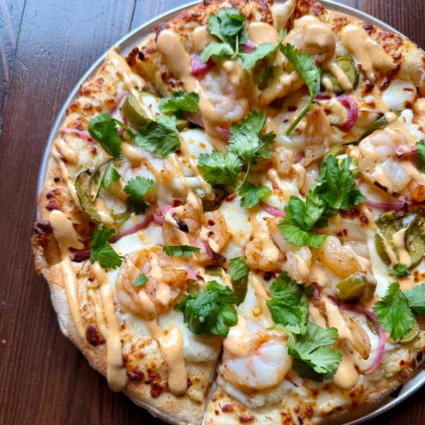 Firebird Tavern's shrimp pizza, topped with cilantro, red onion, jalapeños, and a creamy drizzle.