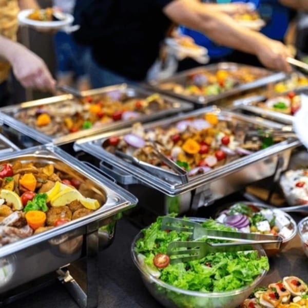 People serving themselves from a buffet of hot dishes and fresh salads at Firebird Tavern.